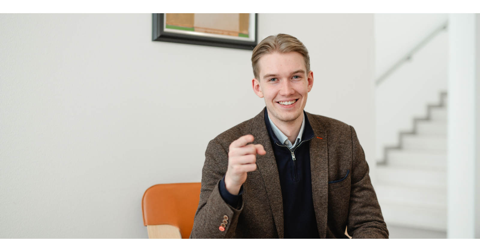 Julius Pentti is sitting in an armchair, smiling and pointing encouragingly straight at the camera.