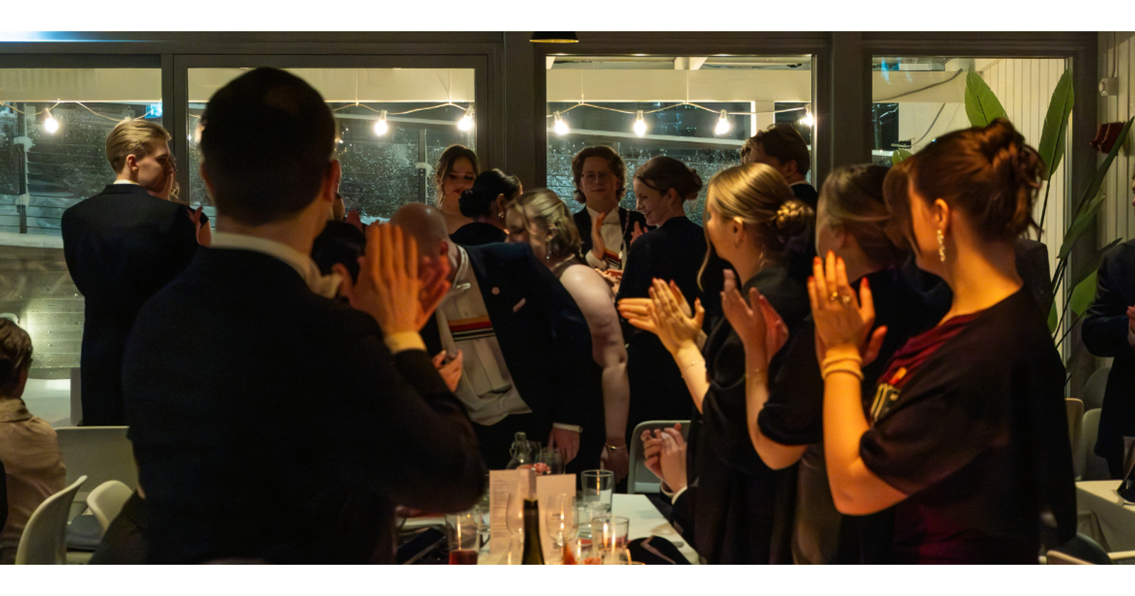 Valokuva vuosijuhlista: Vieraat ovat nousseet seisomaan antamaan aplodit.