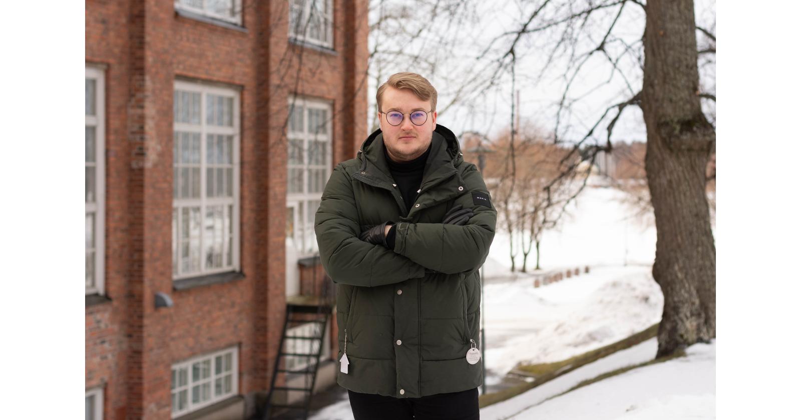 Hallituksen puheenjohtaja Elmo Paloniemi seisoo kädet puuskassa punaisen tiiliseinän edustalla
