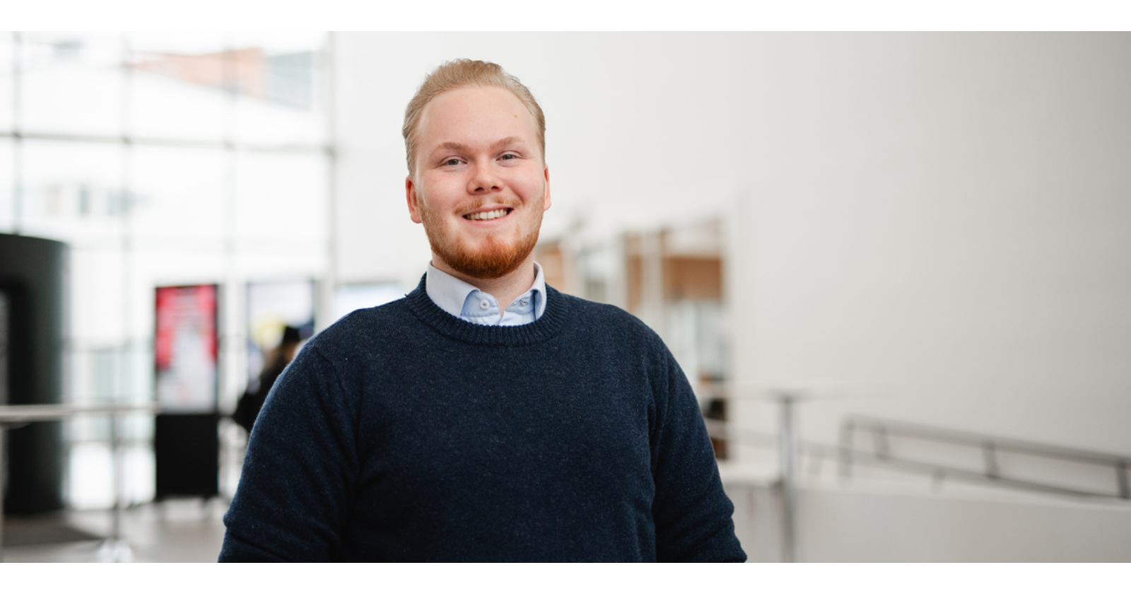 Juuso Tynjälä, VYY:n hallituksen jäsen, hymyilee kameralle. Taustalla on vaaleaseinäinen aula.