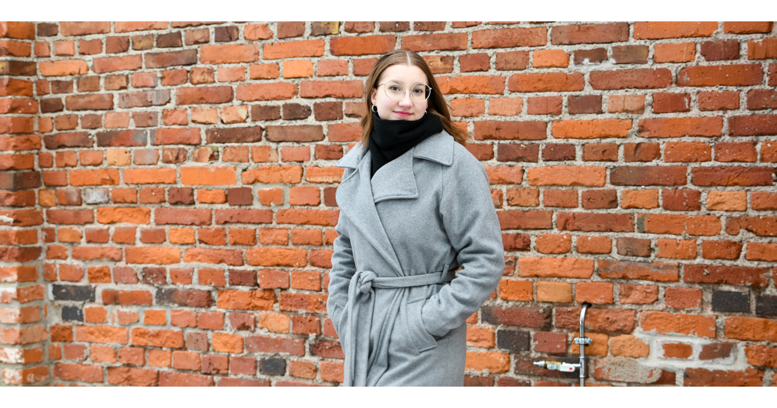 Heidi Elers seisoo punatiilisen seinän edessä ja katsoo kameraan.