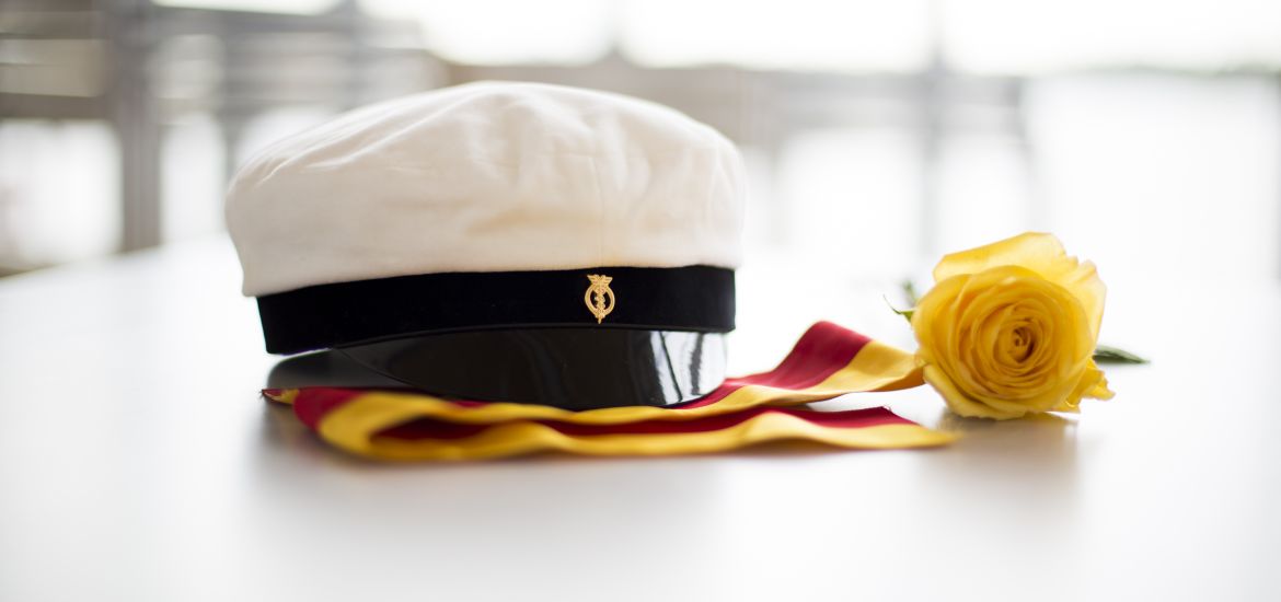 Matriculation cap and a yellow rose on a table